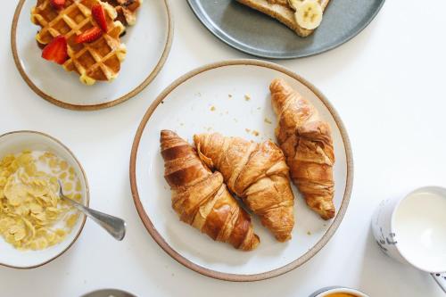 a table topped with plates of croissants and waffles at Apartment Aldea Les Gets - by EMERALD STAY in Les Gets