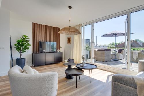 a living room with chairs and tables and a large window at Meerzicht 61 - Luxury 4 person apartment in Uitgeest