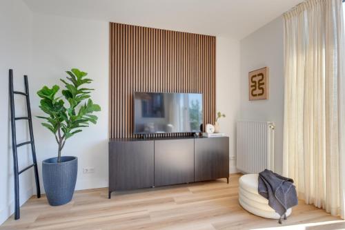 a living room with a tv on a cabinet at Meerzicht 61 - Luxury 4 person apartment in Uitgeest