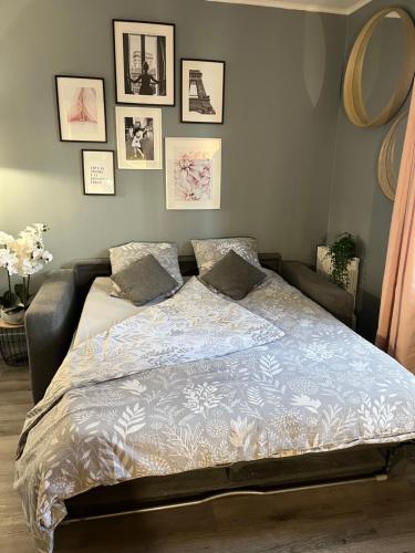 1 cama en un dormitorio con cuadros en la pared en Charmant studio, en Les Lilas