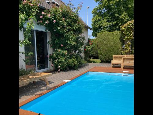 une piscine bleue devant une maison dans l'établissement Zen Cottage - Maison pour 2 avec piscine partagée, à Louvigny