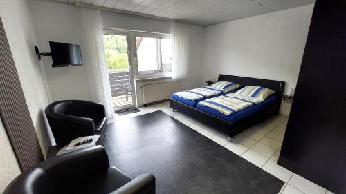 a bedroom with a bed and a chair and a window at Pension Mosella , Appartement-Wohnung mit Balkon und Moselblick in Sankt Aldegund