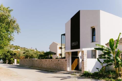 a white building next to a stone wall at LAN-GO SIVOTA Luxury Living in Sivota