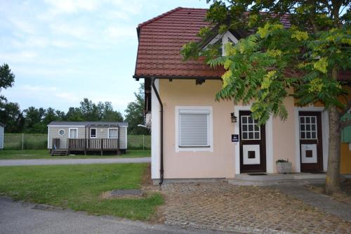 a small white house with a porch and a yard at Aparthouse SUPREME with Terme Catez Swimming Pools Tickets in Čatež ob Savi