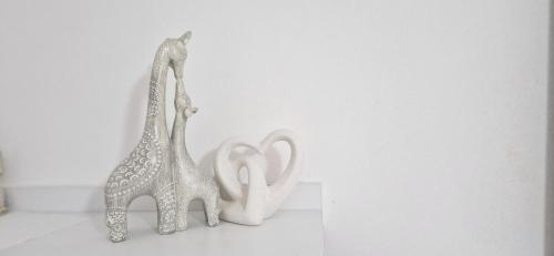 due sculture di giraffe sedute su un muro bianco di Sala apartment's a Sarandë