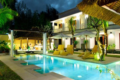 a pool in front of a villa at night at Alam Mimpi Hotel in Lajor