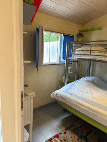 une chambre avec deux lits superposés et une fenêtre dans l'établissement Maison Ile d'oleron 10 min de la plage à pied, parking et jardin, à Foulerot