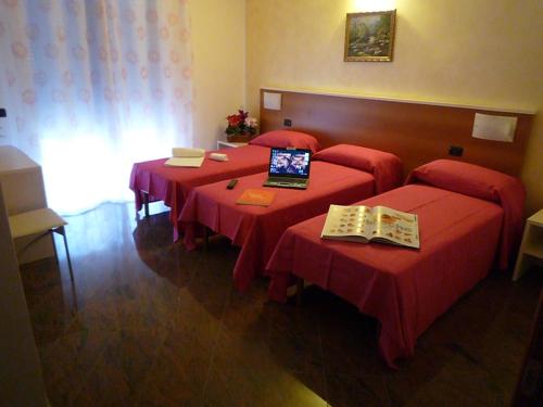 a room with four tables with red covers and a laptop at La Volpe Pescatrice in Castellanza