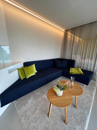 a living room with a blue couch and a table at Seeblick Appartements Henle in Bregenz