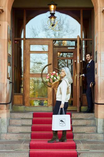 a woman standing on a red carpet holding flowers at Grand Hotel Lund in Lund