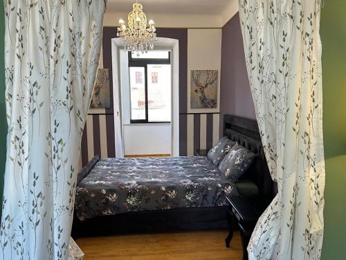 1 dormitorio con 1 cama con cortinas y lámpara de araña en Piazza delle erbe apartment, en Pula