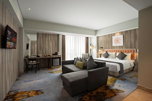a hotel room with a bed and a couch at Grand Orchardz Hotel Kemayoran Jakarta in Jakarta