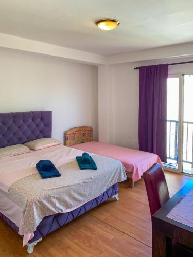 two beds in a bedroom with purple curtains and a table at Villa Dulsinea in Ulcinj