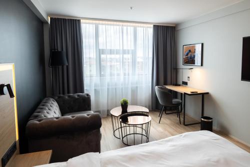 a hotel room with a bed and a couch and a table at Park Inn by Radisson Reykjavik Keflavík Airport in Keflavík