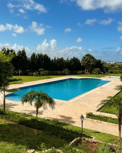 a large swimming pool with palm trees in a park at Appartement de vacances Achakar in Tangier