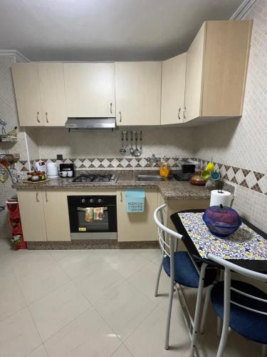 a kitchen with white cabinets and a table with chairs at Appartement de vacances Achakar in Tangier