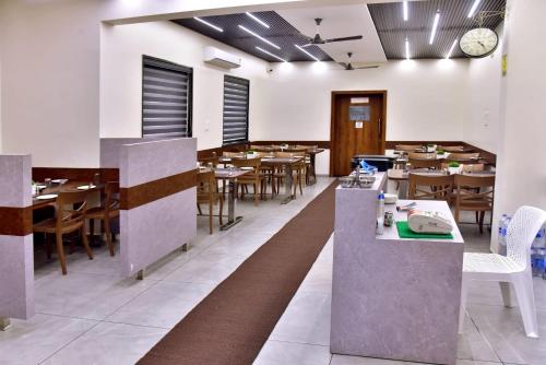 a dining room with tables and chairs and a clock at Hotel Wing Orbit in Bāli