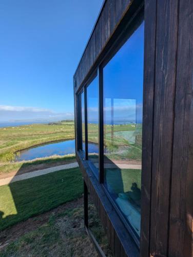 a window on the side of a building looking out at a river at Carrick-a-Rede Luxury Retreat Ballintoy Causeway Coast in Ballintoy