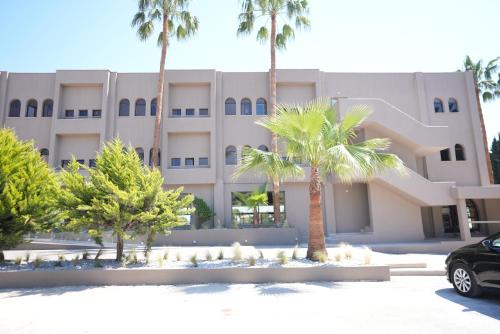a building with palm trees in front of it at Iolida Corfu Resort & Spa by Smile Hotels in Dassia