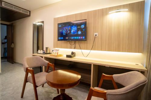 a room with a desk with a tv and two chairs at Mastiff Select Medha Plaza Deoghar in Deoghar