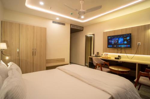a hotel room with a bed and a desk and a tv at Mastiff Select Medha Plaza Deoghar in Deoghar