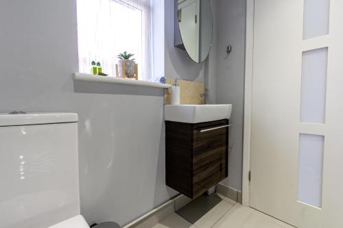 a white bathroom with a sink and a mirror at Stylish Studio-Walk to Windsor/Eton/Thames with Car Park in Datchet