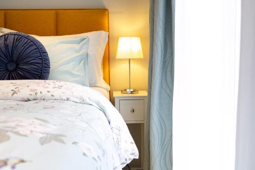 a bedroom with a bed and a lamp on a table at Stylish Studio-Walk to Windsor/Eton/Thames with Car Park in Datchet