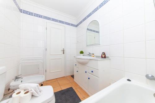 a white bathroom with a toilet and a sink at Seasun Step Apartment in Praia da Rocha in Portimão