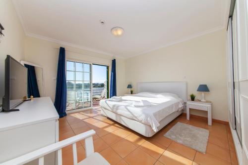 a white bedroom with a bed and a window at Seasun Step Apartment in Praia da Rocha in Portimão