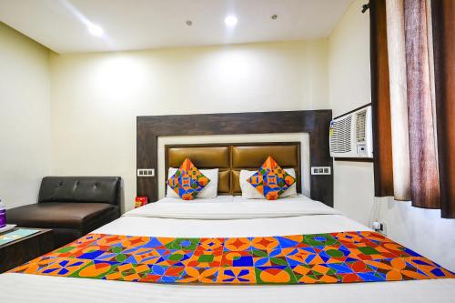 a bedroom with a king sized bed with a colorful quilt at FabHotel Nanda Civil Lines in Ludhiana