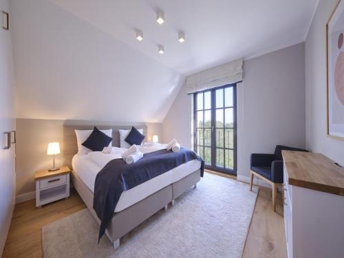 a bedroom with a large bed and a window at Reetland am Meer - LuxusPlus Reetdachvilla mit 4 Schlafzimmern, Außensauna, Loungebereich und Kamin H05 in Dranske