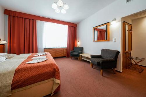 a hotel room with a bed and two chairs at Penzion Homer Poděbrady in Poděbrady