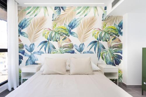 a bedroom with a white bed with a tropical wallpaper at Home2Book Design & Spacious Apartment City Center in Santa Cruz de Tenerife