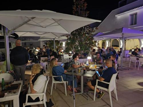 a group of people sitting at tables under umbrellas at Rosa Marina Frontline Beach in Ostuni