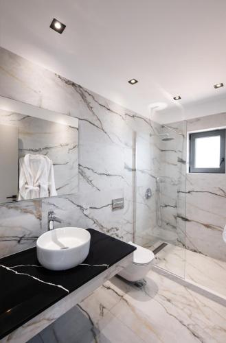 a marble bathroom with a sink and a toilet at Lefkadian Gem Villas in Áyios Nikólaos Nirás