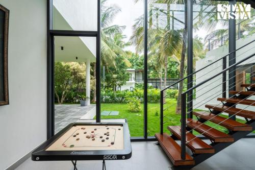 a pool table in a room with windows at StayVista at M Villa with Breakfast Included in Bengaluru