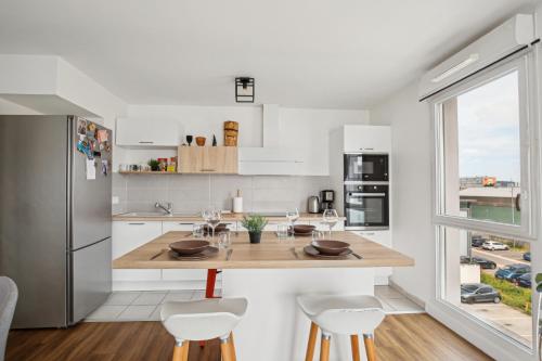 une cuisine avec une table en bois et des armoires blanches dans l'établissement Chic and comfortable apart with parking and balcony, à Bezons