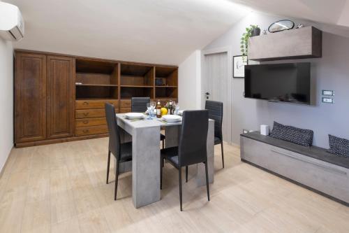 Un comedor con una mesa con sillas y un televisor. en Il Nido dei Sogni, en Imperia