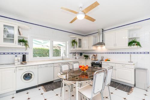 a kitchen with white cabinets and a table and chairs at VILLA DO VALE- Stunning Family Villa with Pool in Tavira