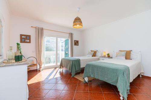 a bedroom with two beds and a large window at VILLA DO VALE- Stunning Family Villa with Pool in Tavira