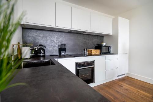a kitchen with white cabinets and a black counter top at River & Castle at Ryedale House in York