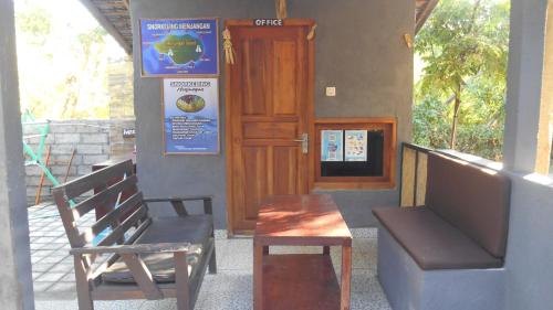 a bench and a table and a chair in front of a door at Taman Menjangan homestay by SnorkelingMenjangan in Banyuwedang