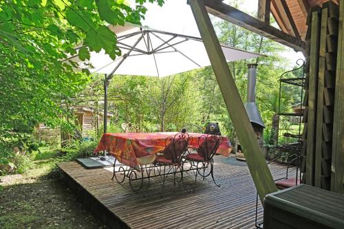 a table and chairs under an umbrella on a deck at Charmant chalet aux portes d'Epinal in Épinal