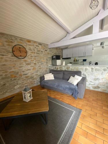 a living room with a couch and a clock on the wall at Les granges du chiron in La Garnache
