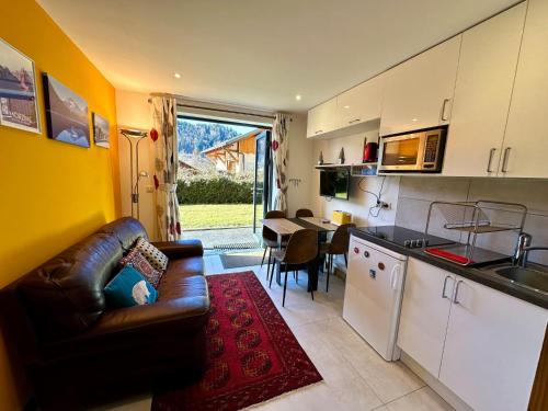 une cuisine et un salon avec un canapé et une table dans l'établissement The Haven Montriond jardin 4 personnes, à Montriond