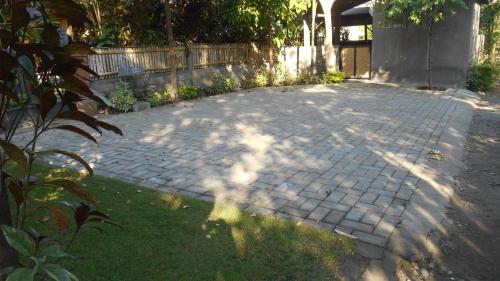 a brick patio with grass and a fence and trees at Taman Menjangan homestay by SnorkelingMenjangan in Banyuwedang