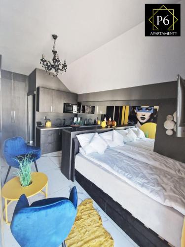 a bedroom with a large bed and blue chairs at P6 Apartament Mini Light Black in Pisz