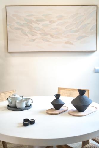 a white dining room table with a painting on the wall at Elements Milfontes - Japandi Designed House - City Center in Vila Nova de Milfontes