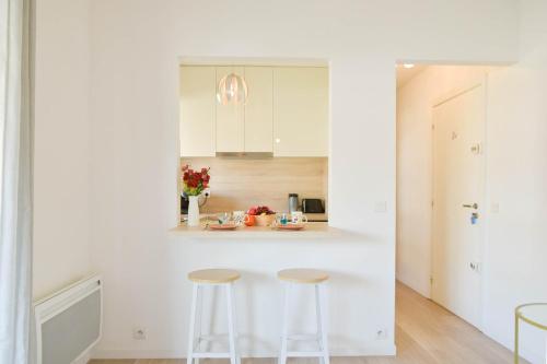 une cuisine avec des placards blancs et deux tabourets dans l'établissement Palm Beach Studio with Terrace 150m from beaches, à Cannes