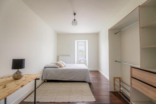 une chambre blanche avec un lit et une table dans l'établissement La Listracaise - Charmante maison pour 5 voyageurs, à Listrac-Médoc